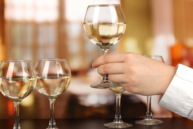 Tasting white wine on room background